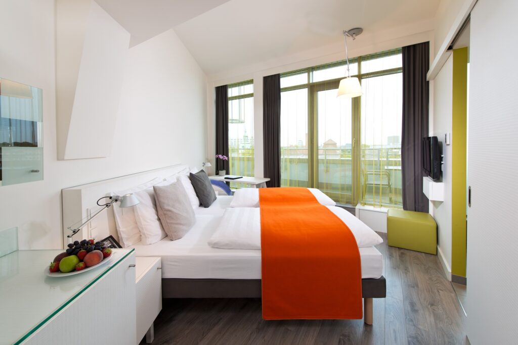 Modern hotel room with bright orange accents on the bedding